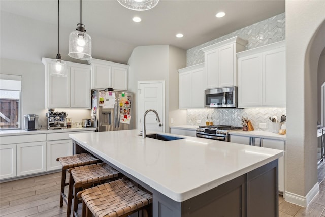 kitchen featuring sink, a breakfast bar, appliances with stainless steel finishes, an island with sink, and white cabinets