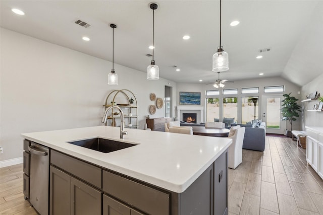 kitchen featuring hanging light fixtures, sink, stainless steel dishwasher, and a kitchen island with sink