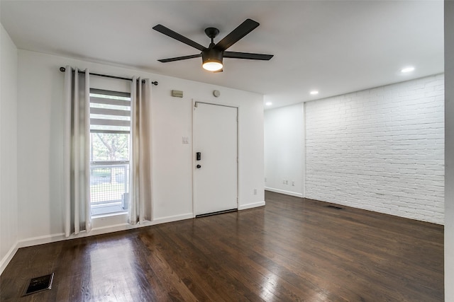 foyer entrance featuring brick wall, dark wood-type flooring, and ceiling fan