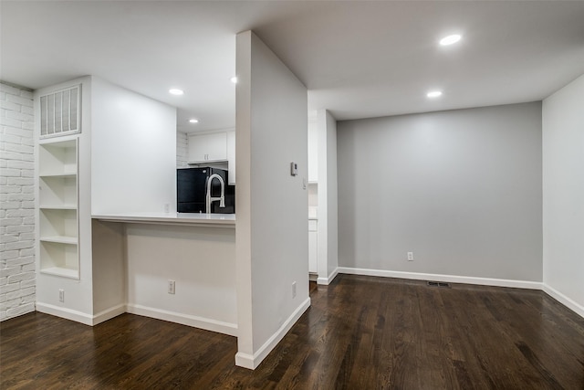 kitchen featuring black fridge, white cabinetry, kitchen peninsula, and dark wood-type flooring