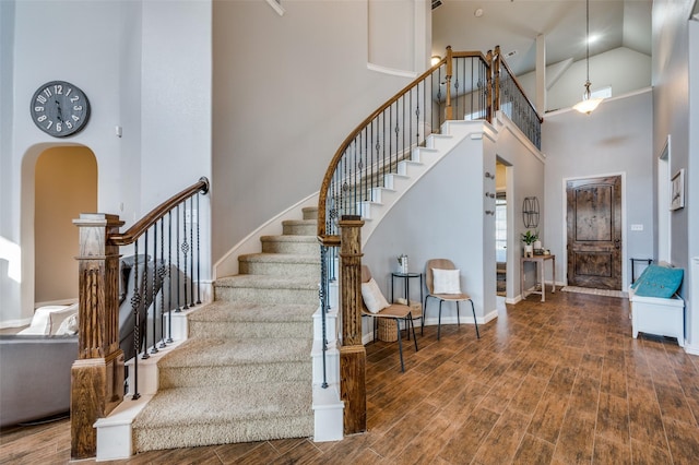 stairs with wood-type flooring and high vaulted ceiling