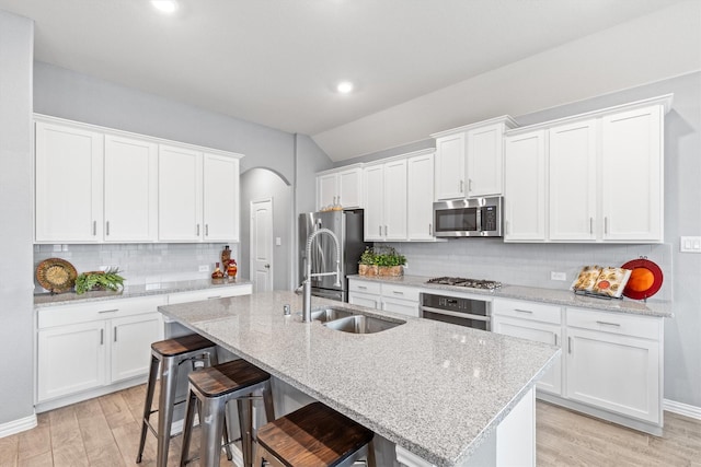 kitchen featuring an island with sink, appliances with stainless steel finishes, a breakfast bar area, and white cabinets