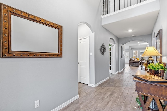 corridor featuring a towering ceiling and light hardwood / wood-style flooring