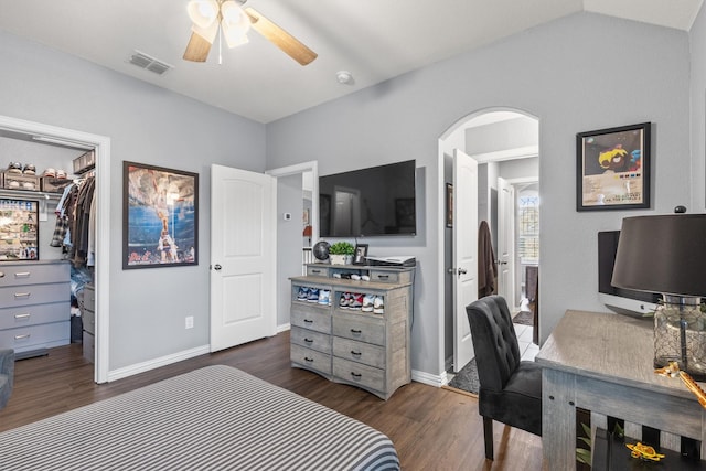 bedroom featuring a walk in closet, vaulted ceiling, dark hardwood / wood-style floors, a closet, and ceiling fan