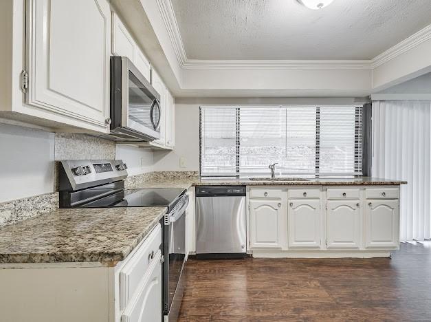 kitchen with white cabinetry, appliances with stainless steel finishes, sink, and crown molding