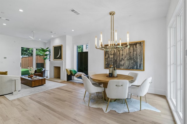 4529 Fairway, Highland Park, TX 75219 - dining space featuring light wood-style flooring, plenty of natural light, a chandelier, recessed lighting, and a fireplace with raised hearth