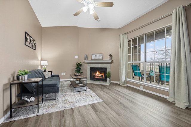 sitting room featuring lofted ceiling, baseboards, a tiled fireplace, and wood finished floors