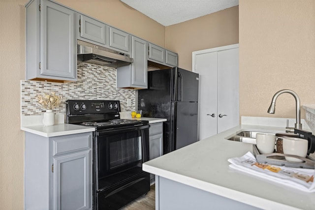 4113 Esters Rd Unit 609, Irving, TX 75038 - kitchen with light countertops, tasteful backsplash, under cabinet range hood, black appliances, and gray cabinets