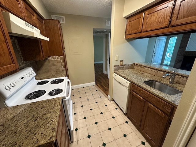 kitchen featuring sink, white appliances, light stone counters, kitchen peninsula, and a textured ceiling