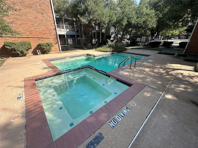 view of swimming pool featuring a hot tub and a patio