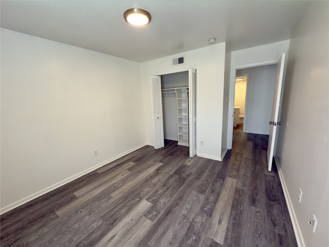 unfurnished bedroom with dark wood-type flooring and a closet