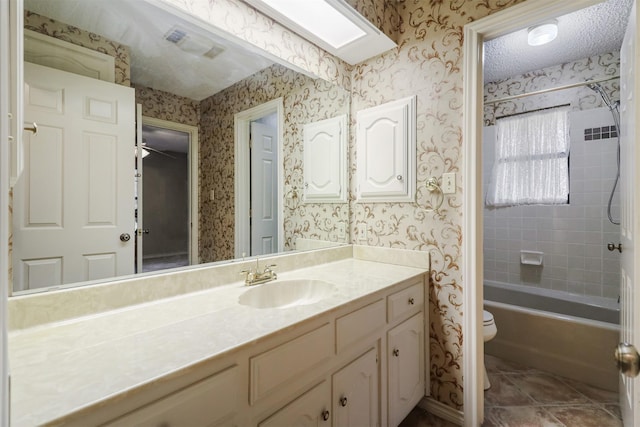 full bathroom with toilet, tiled shower / bath, a skylight, a textured ceiling, and vanity