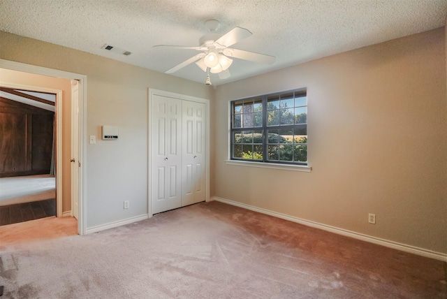 unfurnished bedroom with ceiling fan, carpet flooring, a textured ceiling, and a closet