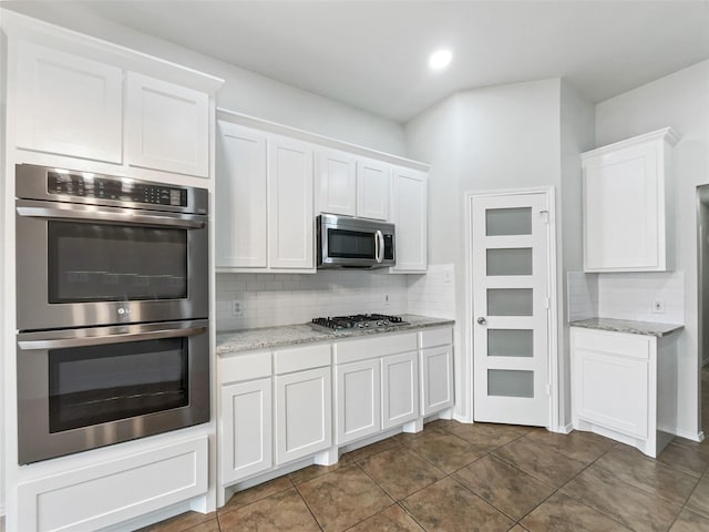 kitchen featuring white cabinetry, tasteful backsplash, stainless steel appliances, and light stone counters