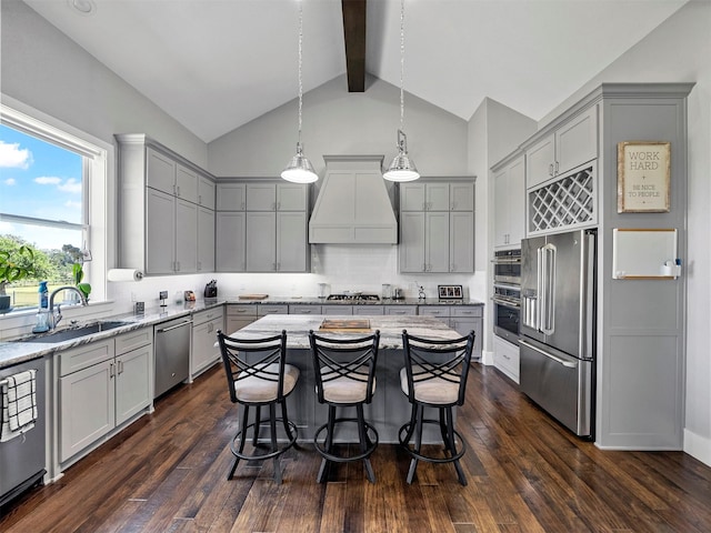 kitchen with gray cabinets, premium range hood, appliances with stainless steel finishes, hanging light fixtures, and a center island