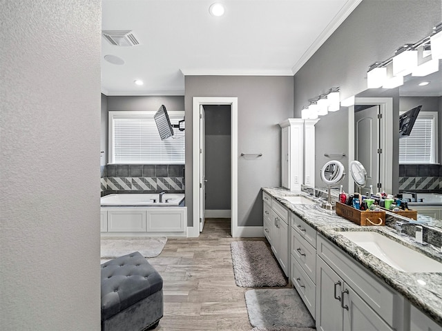 bathroom with vanity, crown molding, wood-type flooring, and a bathing tub