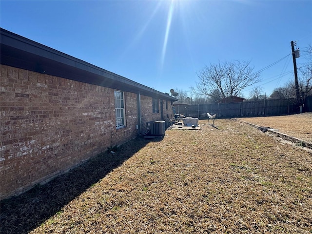 view of yard with central AC unit and fence