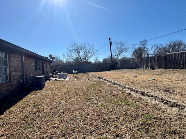 view of yard with a fenced backyard and central AC