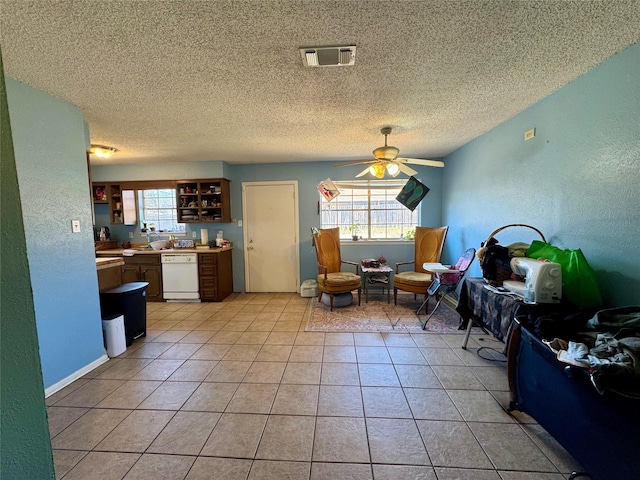 interior space with a ceiling fan, a textured ceiling, light tile patterned flooring, a textured wall, and visible vents
