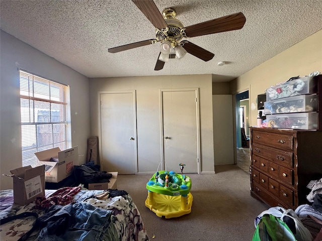 carpeted bedroom with a ceiling fan, a textured ceiling, and two closets