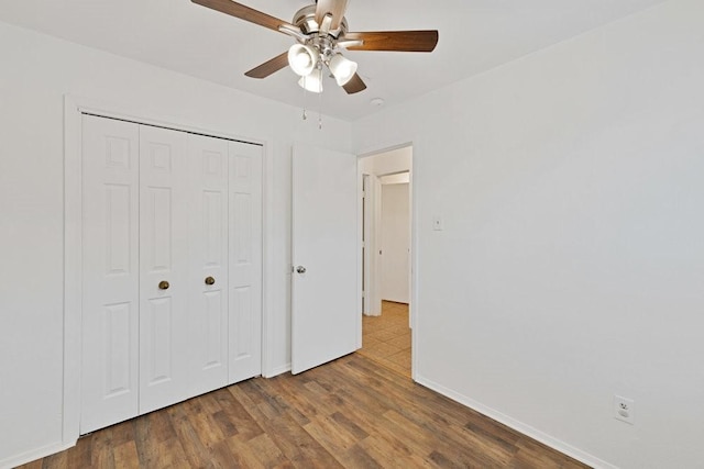 unfurnished bedroom featuring ceiling fan, a closet, wood finished floors, and baseboards