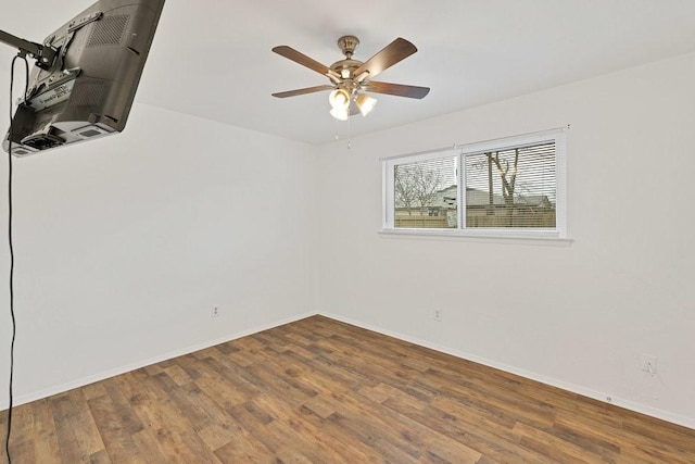 unfurnished room featuring a heating unit, wood finished floors, a ceiling fan, and baseboards