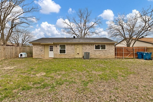 rear view of house with brick siding, a lawn, cooling unit, and a fenced backyard