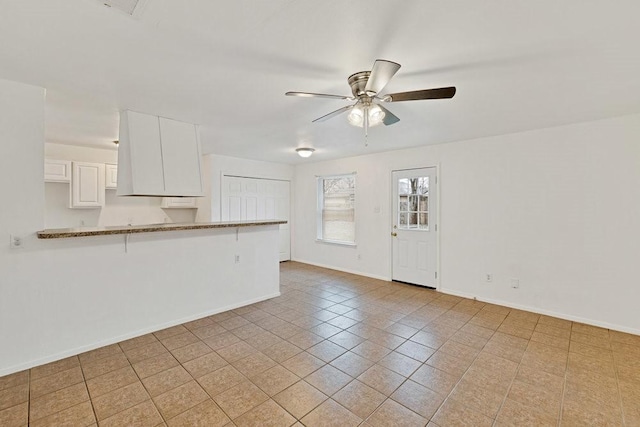 unfurnished living room featuring a ceiling fan and baseboards