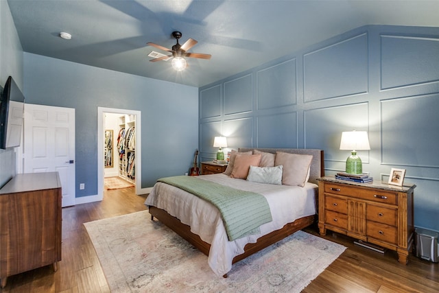 bedroom with dark hardwood / wood-style flooring, a spacious closet, a closet, and ceiling fan