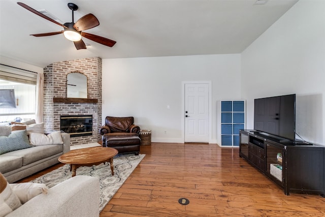 living room with hardwood / wood-style flooring, ceiling fan, a fireplace, and vaulted ceiling