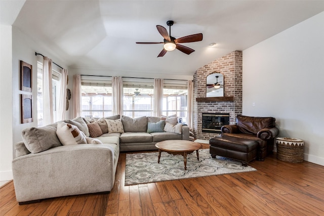 living room featuring vaulted ceiling, ceiling fan, a fireplace, and light hardwood / wood-style flooring