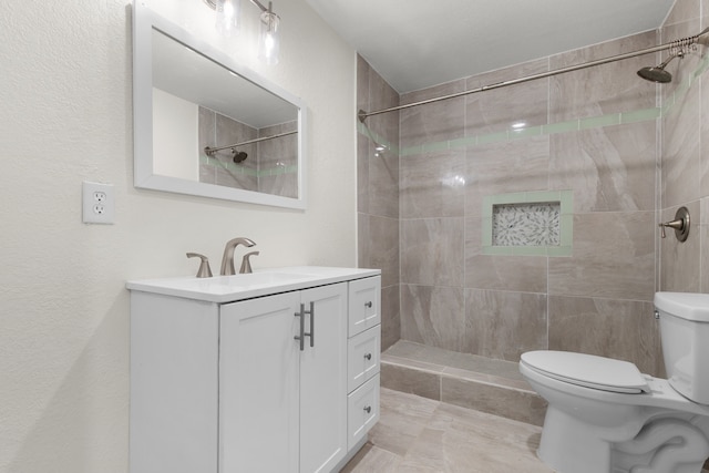 bathroom featuring tiled shower, vanity, and toilet