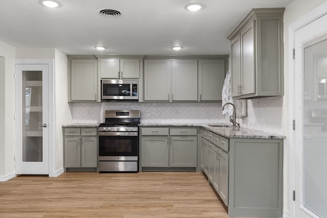 kitchen with gray cabinets, appliances with stainless steel finishes, and light hardwood / wood-style flooring