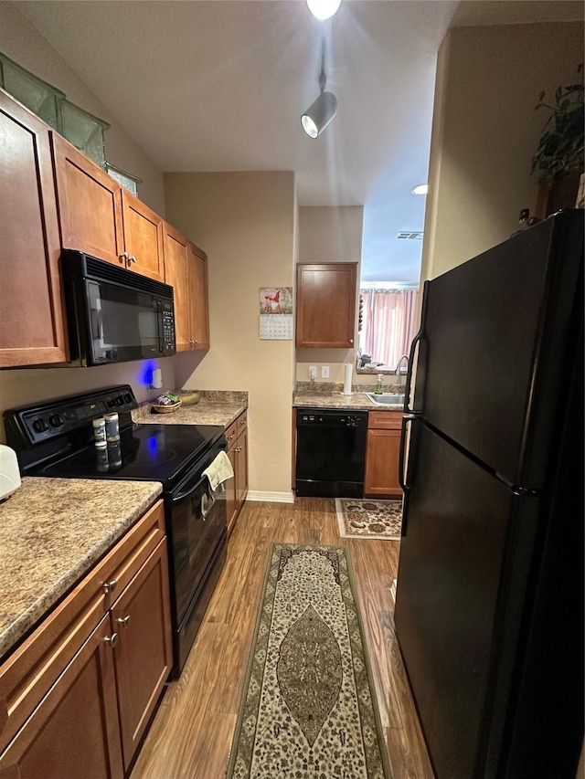 kitchen featuring sink, light hardwood / wood-style floors, and black appliances