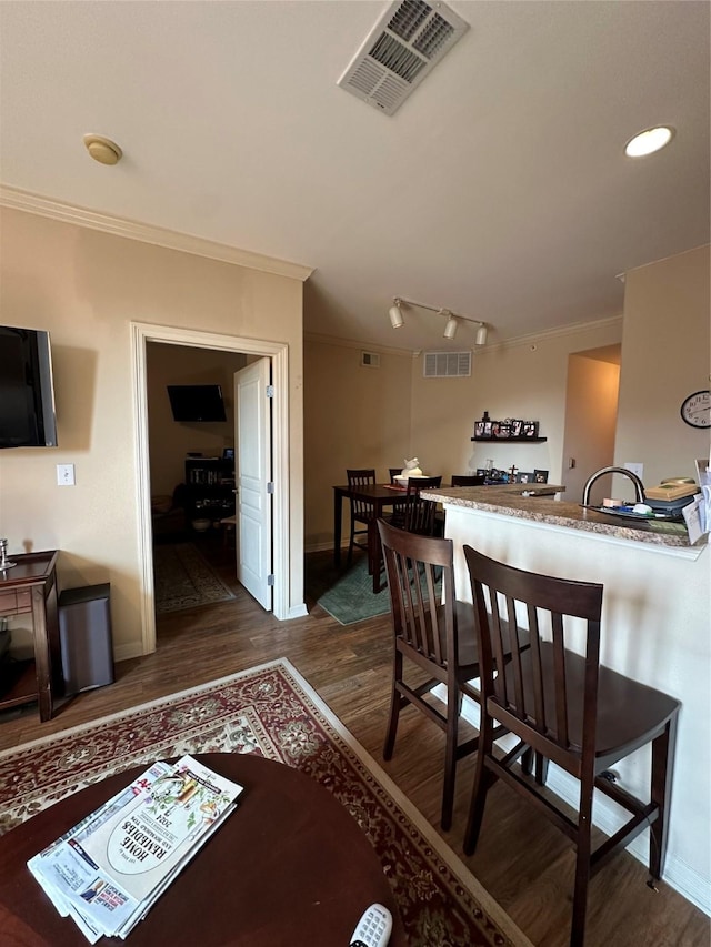 dining room featuring crown molding, dark wood-type flooring, and track lighting