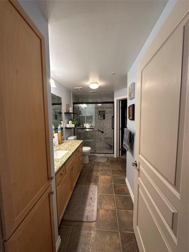 bathroom featuring vanity, toilet, an enclosed shower, and a textured ceiling