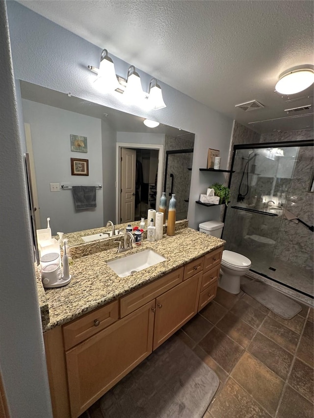 bathroom featuring vanity, a textured ceiling, a shower with shower door, and toilet