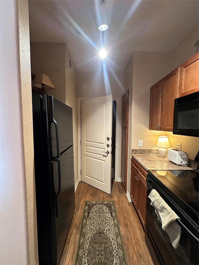 kitchen with hardwood / wood-style floors and black appliances