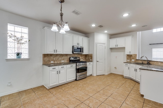 kitchen featuring stainless steel appliances, sink, dark stone counters, and white cabinets