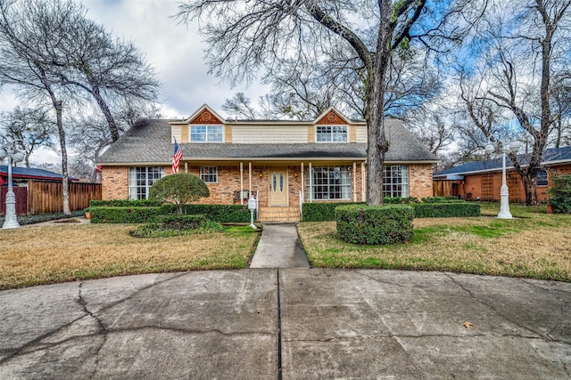 view of front of property featuring fence, a front lawn, and brick siding