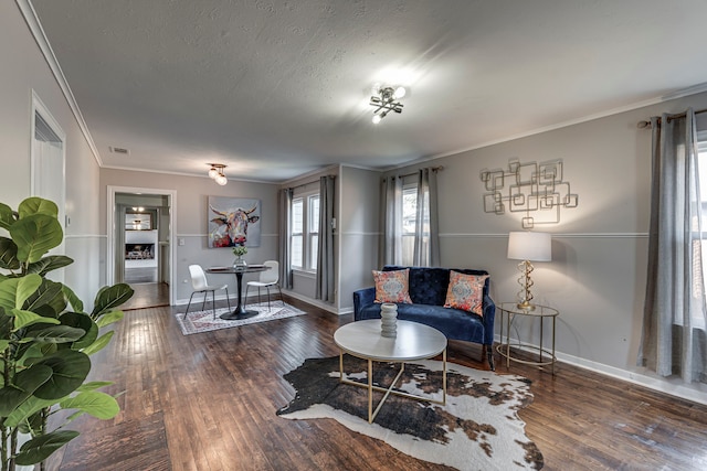 living room with ornamental molding, dark wood-type flooring, and a textured ceiling