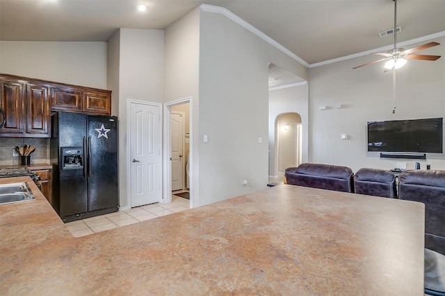 kitchen featuring crown molding, light tile patterned floors, decorative backsplash, and black refrigerator with ice dispenser