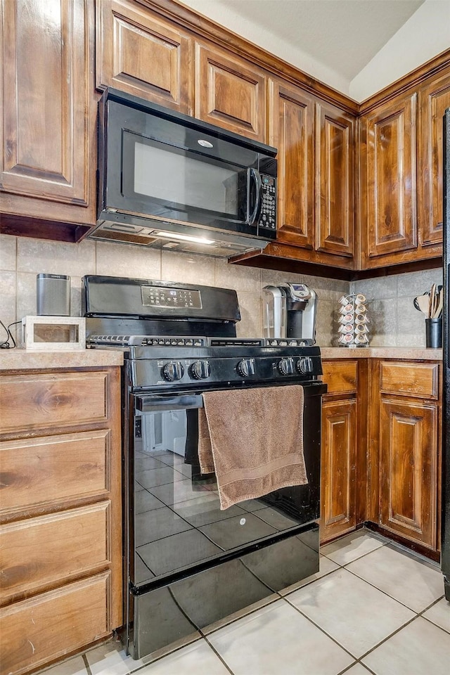 kitchen with light tile patterned floors, decorative backsplash, and black appliances