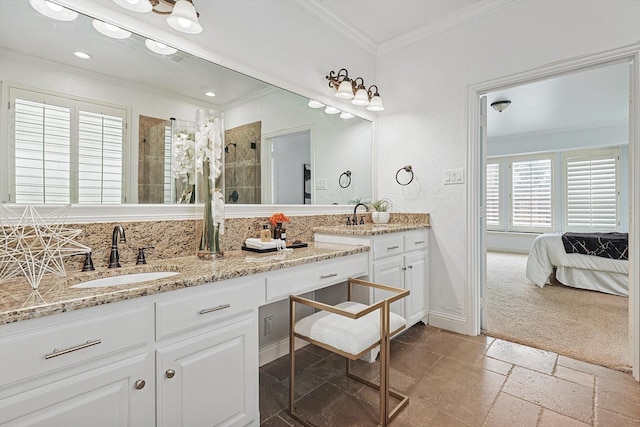 bathroom featuring double vanity, a stall shower, stone tile flooring, ornamental molding, and a sink