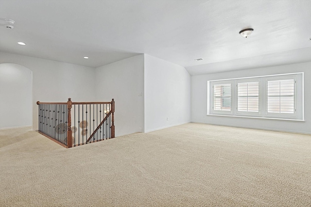 unfurnished room with baseboards, lofted ceiling, recessed lighting, arched walkways, and carpet flooring