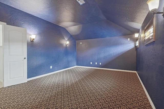 carpeted home theater room featuring vaulted ceiling, a textured wall, visible vents, and a textured ceiling