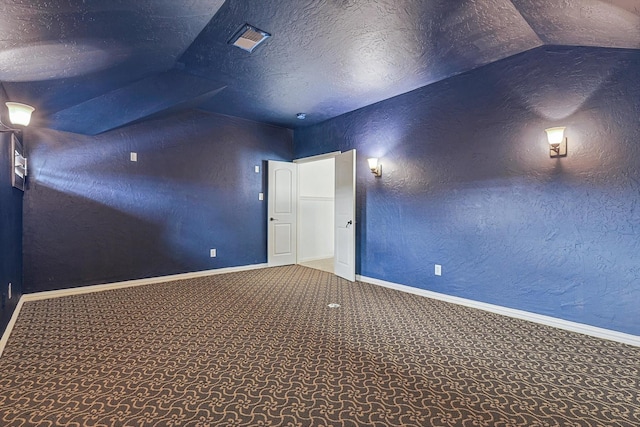 carpeted spare room featuring vaulted ceiling, a textured ceiling, baseboards, and a textured wall