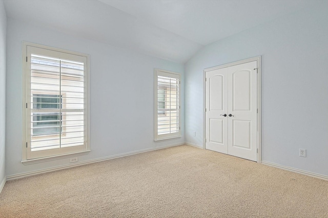 unfurnished bedroom featuring baseboards, carpet floors, lofted ceiling, and a closet