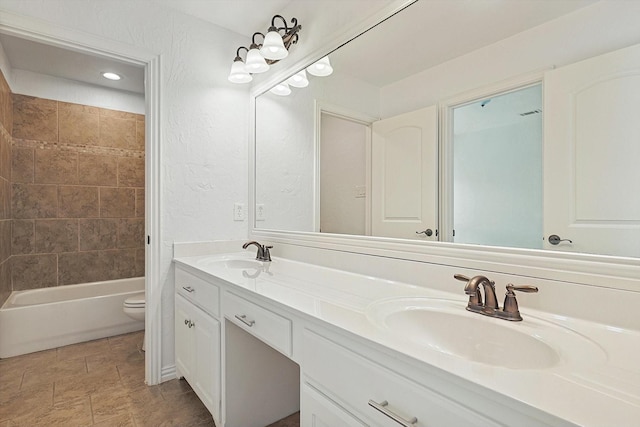 bathroom with double vanity, toilet, tub / shower combination, and a sink