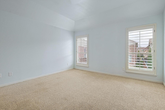 spare room featuring light colored carpet and baseboards